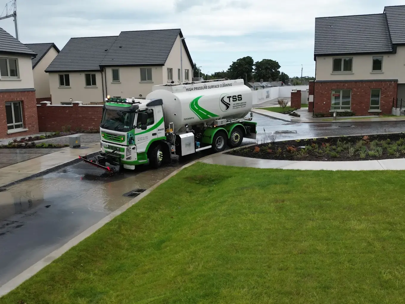 Top Sweep high-pressure surface cleaning jet washer truck removing construction debris and mud from a residential estate road